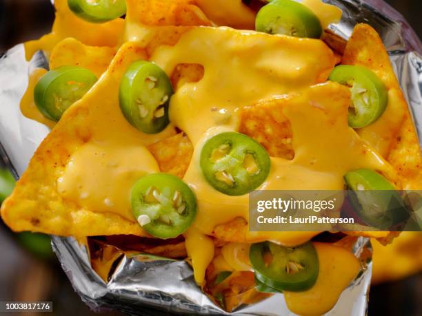 nacho-tortillachips in een zak met kaassaus en jalapenos - chips bag stockfoto's en -beelden