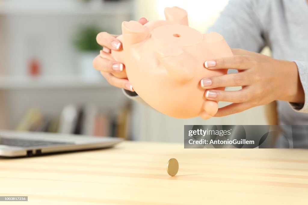 Mujer arruinada comprobando contenido caja alcancía