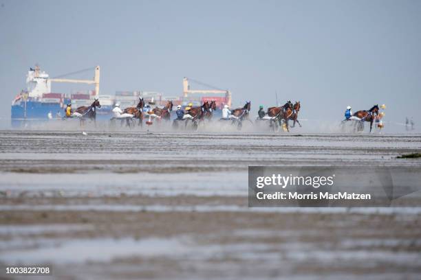 Cargo ship passes during the annual horse buggy races on the mudflats at Duhnen on July 22, 2018 in Cuxhaven, Germany. The races, which in German are...