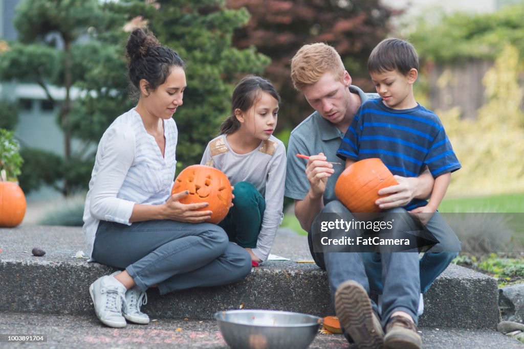 Multiethnic family carving pumpkins together