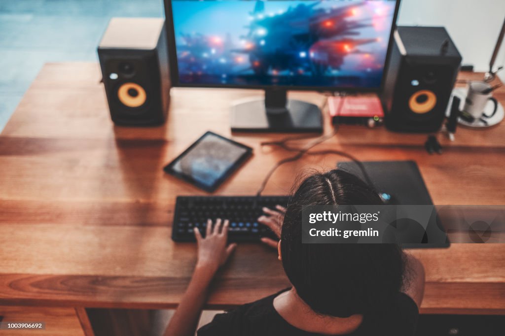 Young woman playing video games on computer at home