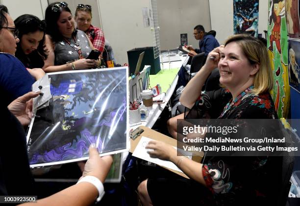 Artist Karen Hallion signs her work for fans during Preview Night during the San Diego Comic-Con at the San Diego Convention Center in San Diego on...