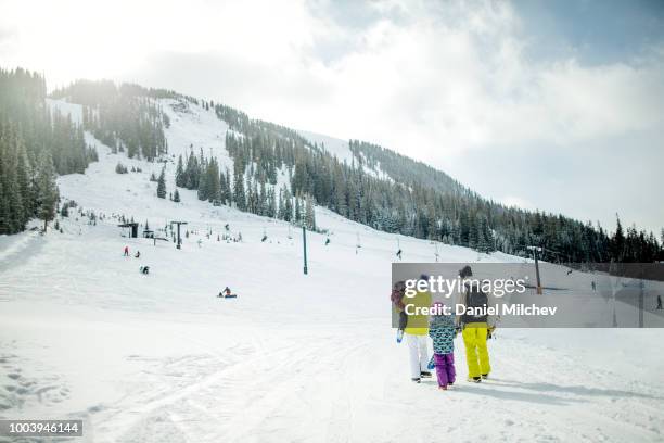 mixed race family walking on snow at a ski resort in colorado during the winter. - keystone stock-fotos und bilder