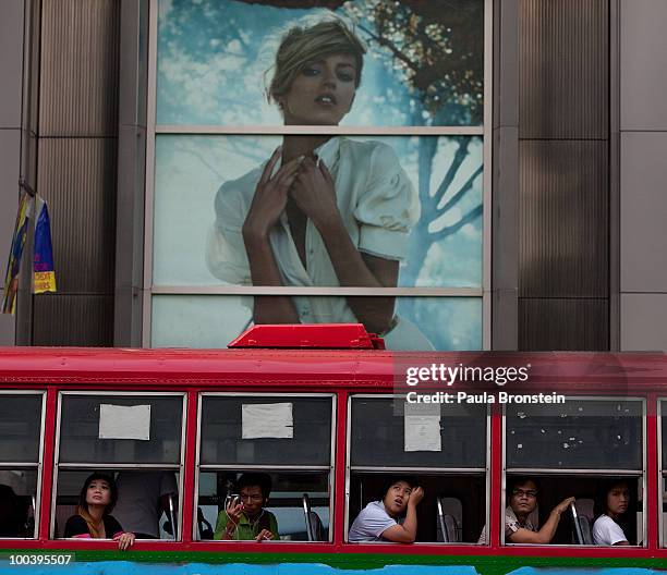 Bangkok residents look out of the bus windows at the burned CentralWorld shopping mall on May 24, 2010 in Bangkok, Thailand. Bangkok is slowly...