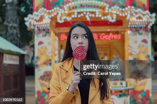 Young brunette woman with lollipop in amusement park Young brunette woman with lollipop in amusement park