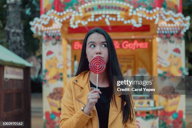 young brunette woman with lollipop in amusement park - draaimolen stockfoto's en -beelden