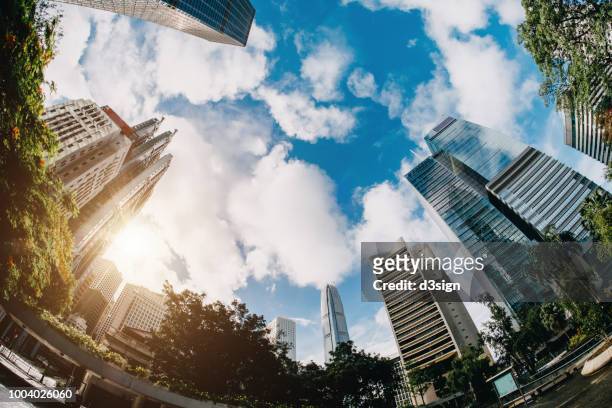 low angle view of contemporary corporate skyscrapers and urban park in financial district of hong kong on a fresh bright morning - fish eye lens stock pictures, royalty-free photos & images