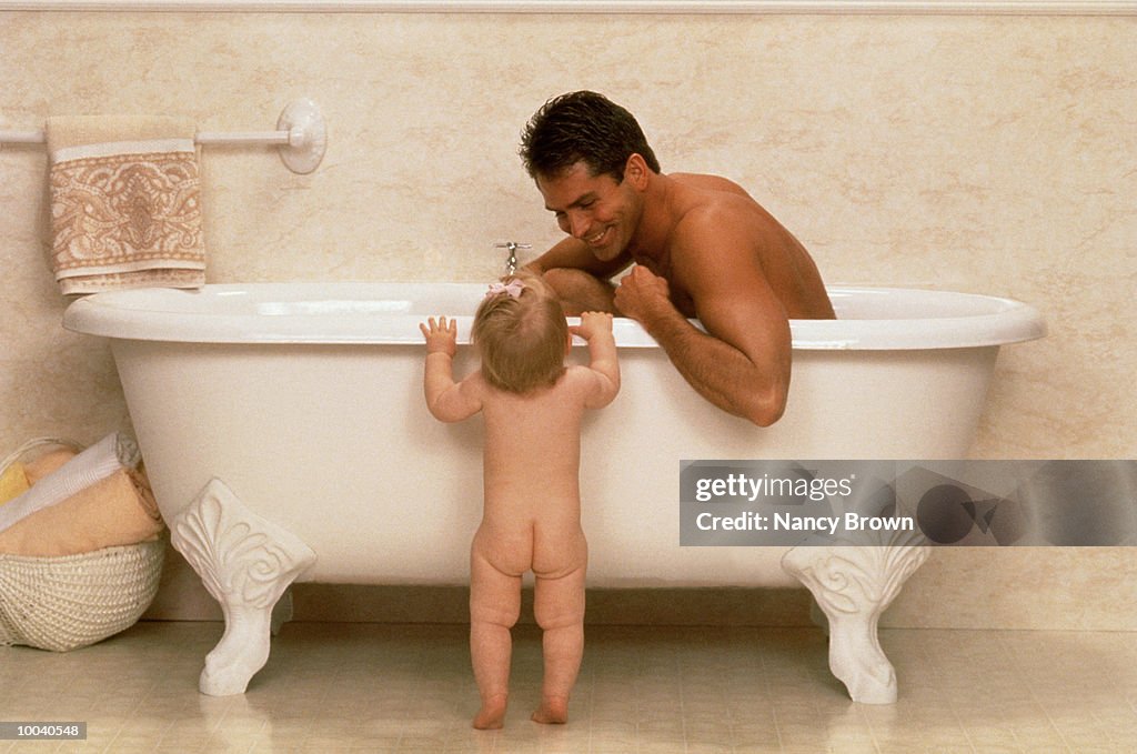 DAD IN TUB WITH BABY STANDING OUTSIDE TUB