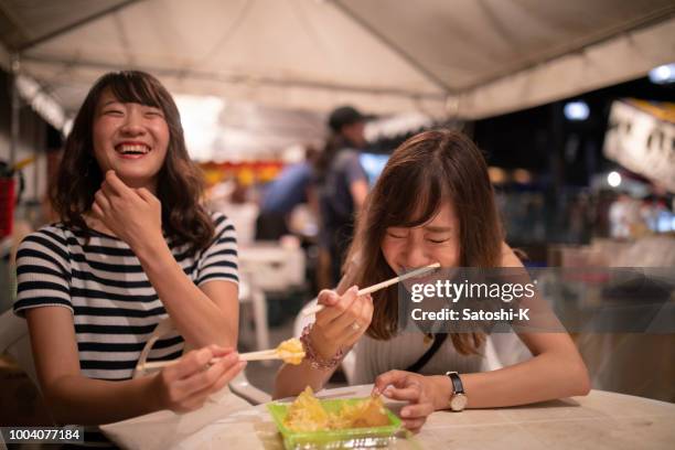 young female friends enjoying in night festival - night market stock pictures, royalty-free photos & images