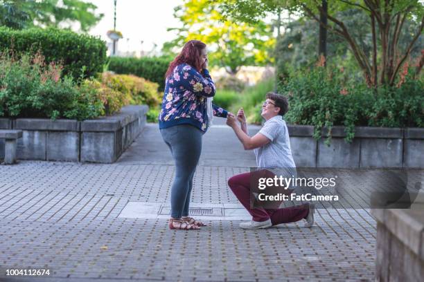 vrouw stelt aan haar vrouwelijke partner in een stadsplein - gay marriage stockfoto's en -beelden