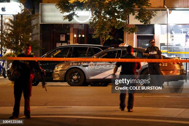 Toronto Police officers walk the scene at Danforth St. At the scene of a shooting in Toronto, Ontario, Canada on July 23, 2018. - A gunman opened...