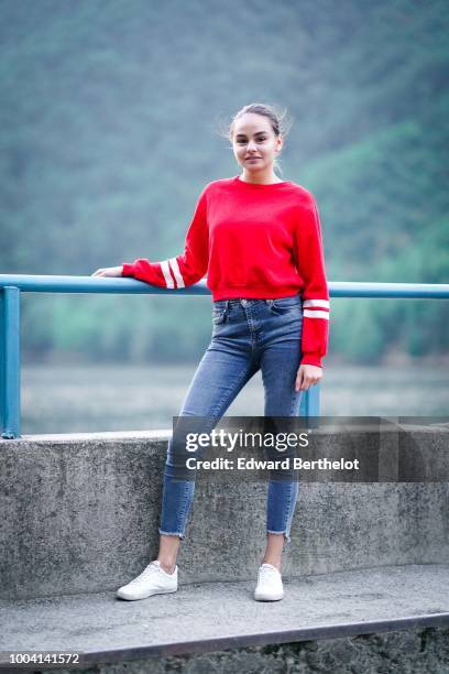 Model wears a red pullover, blue denim jeans , white sneakers shoes, during Feeric Fashion Week 2018, on July 22, 2018 in Sibiu, Romania.