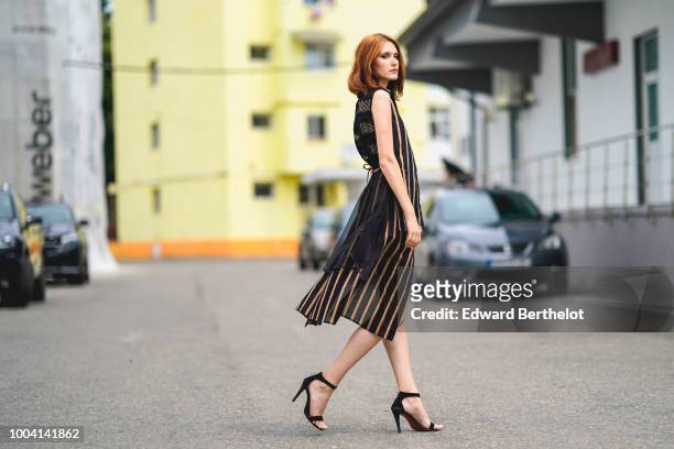 Dariana Cerciu wears a striped sleeveless dress with black lace, black heels shoes, during Feeric Fashion Week 2018, on July 22, 2018 in Sibiu,...
