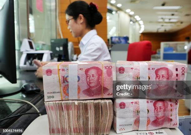 An employee counts 100-yuan notes at a bank in Nantong in China's eastern Jiangsu province on July 23, 2018. - China on July 23 rejected accusations...