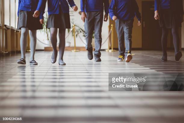 groep studenten wandelen door de hal van de school - uniform stockfoto's en -beelden