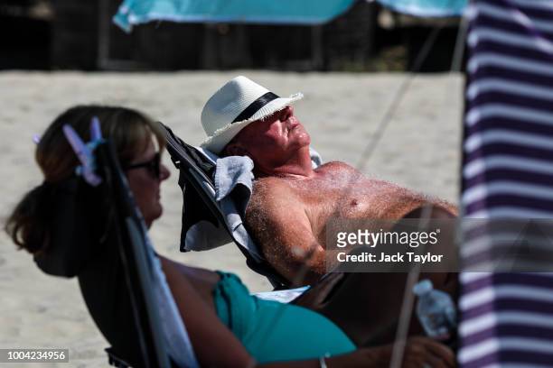 Beachgoers lie in the sun on West Wittering Beach during hot weather on the first day of the Summer school holidays on July 23, 2018 in Chichester,...