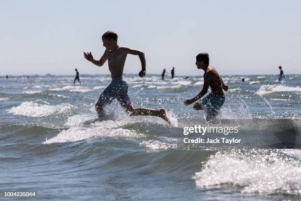 Beachgoers play in the sea on West Wittering Beach during hot weather on the first day of the Summer school holidays on July 23, 2018 in Chichester,...