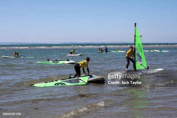 Young people learn to windsurf on West Wittering Beach during hot weather on the first day of the Summer school holidays on July 23, 2018 in...