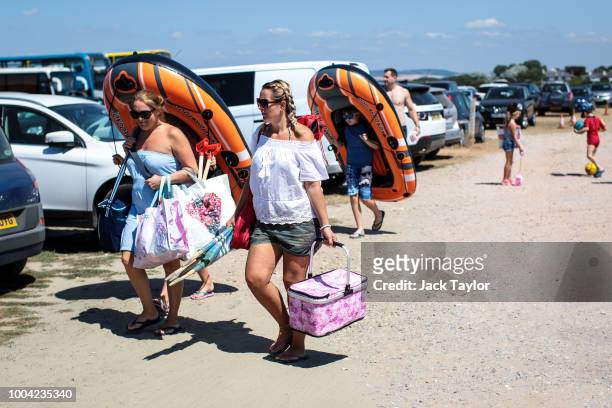 Beachgoers arrive at West Wittering Beach during hot weather on the first day of the Summer school holidays on July 23, 2018 in Chichester, England....