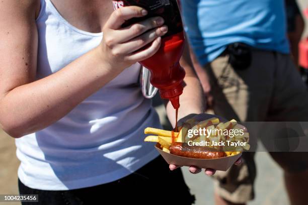 Beachgoers add sauce to their food at a stall by West Wittering Beach during hot weather on the first day of the Summer school holidays on July 23,...