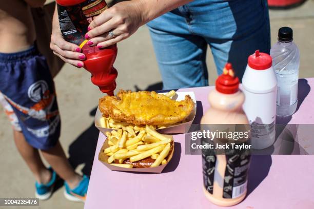 Beachgoers add sauce to their food at a stall by West Wittering Beach during hot weather on the first day of the Summer school holidays on July 23,...