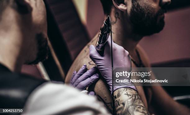 artista del tatuaje hacer el tatuaje en el hombro de un hombre - arm tattoos for black men fotografías e imágenes de stock