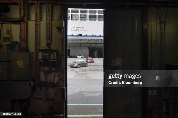 New Mercedes-Benz automobiles drive out of the roll-on roll-off vessel Delphine, operated by Cldn Ro-Ro SA, seen from inside a shipping container at...