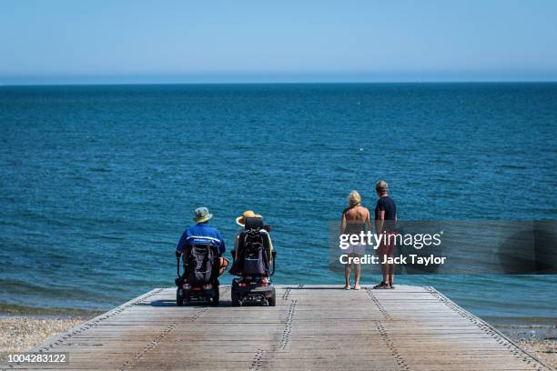 Couples look out to sea from Selsey Beach during hot weather on the first day of the Summer school holidays on July 23, 2018 in Chichester, England....