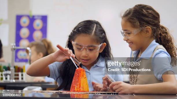 little girls perform experiment with volcanic model at school - sweet little models stock pictures, royalty-free photos & images
