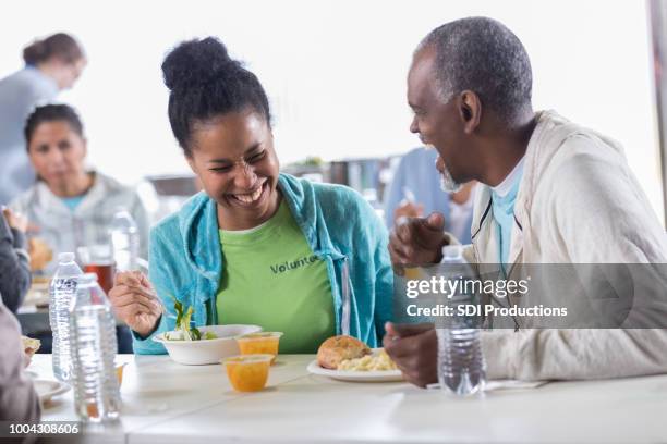 food bank volunteers enjoy a food break together - homeless shelter man stock pictures, royalty-free photos & images