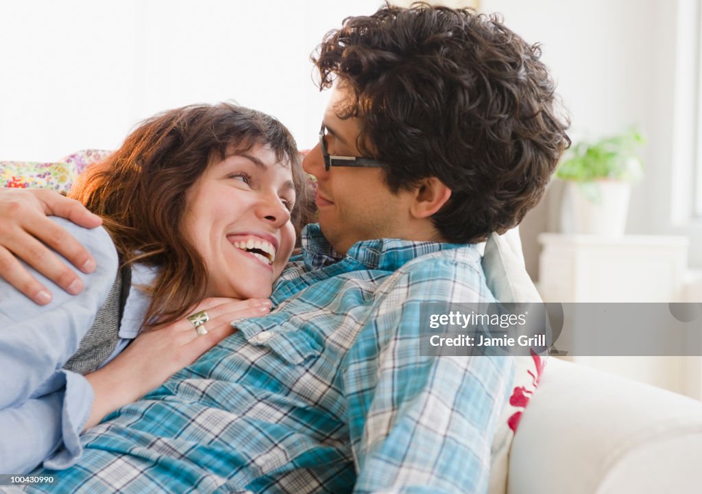 Young couple cuddling on couch together