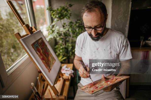 mature artist on his art studio - making painting stock pictures, royalty-free photos & images