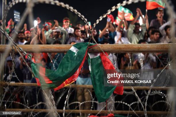 Flag of the Pakistan Tehreek-e-Insaf is seen in foreground as supporters of Pakistani cricket star-turned-politician and head of the Pakistan...