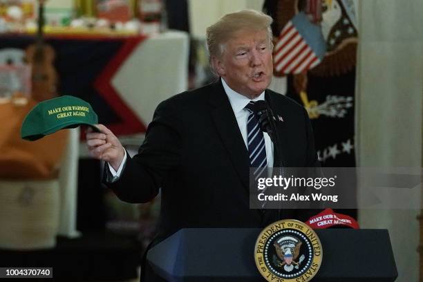 President Donald Trump holds up a "Make Our Farmers Great Again" hat as he speaks during the 2018 Made in America Product Showcase event July 23,...