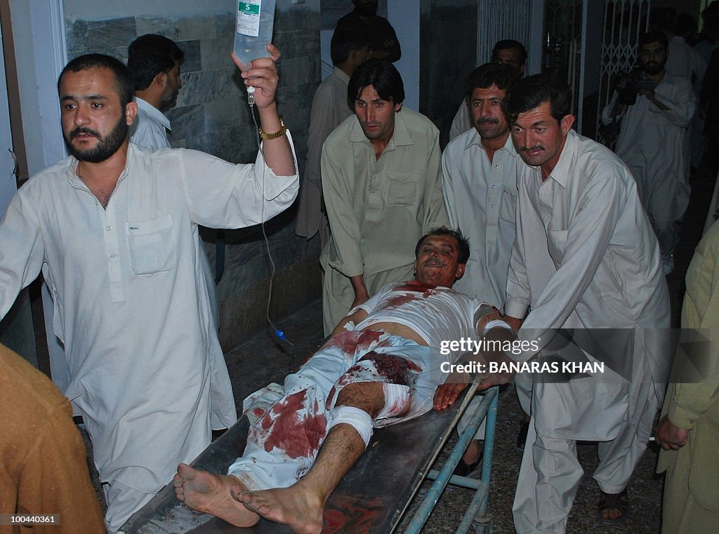 Pakistani peoples shift an injured bomb