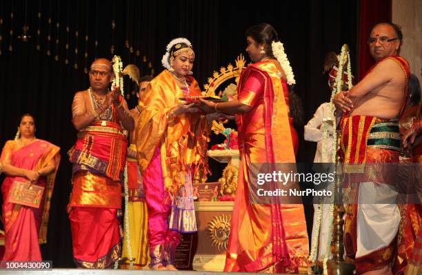 Young Bharatnatyam dancer is presented her ghungroos by her teacher before the commencement of a Bharatnatyam Arangetram performance in Toronto,...