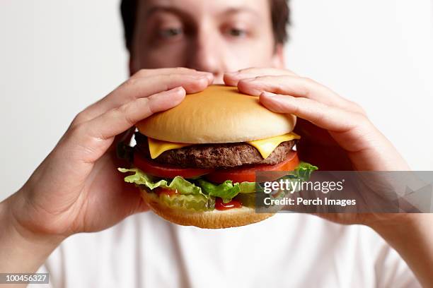 man holding cheeseburger - hand holding burger stock pictures, royalty-free photos & images