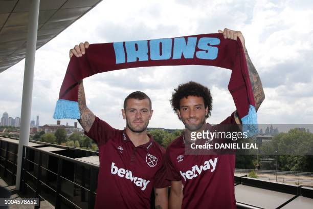West Ham United's Brazlian midfielder Felipe Anderson and West Ham United's English midfielder Jack Wilshere pose with a scarf in the team colours...