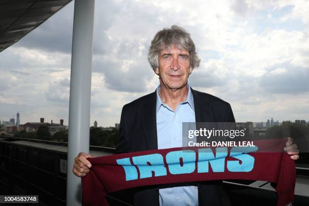 West Ham United's Chilean manager Manuel Pellegrini poses with a scarf in the team colours during a photocall for the unveiling of the club's new...