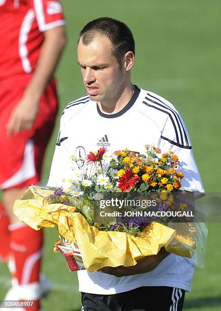 Germany's defender Heiko Westermann carries a bouquet off the pitch at the beginning of a training match Germany vs Sued Tyrol FC at the team's...