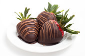 Close up of three chocolate covered strawberries on a white plate