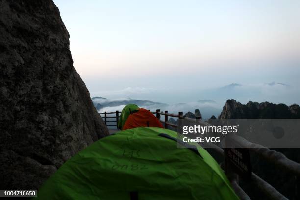 Tents set up by backpackers line up along a plank road on a 2,000-meter-high cliff face of the Laojun Mountain during a camping trip on July 21, 2018...