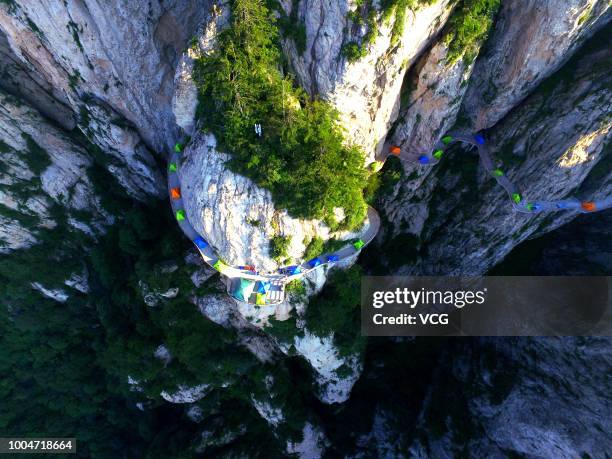 Aerial view of tents set up by backpackers lining up along a plank road on a 2,000-meter-high cliff face of the Laojun Mountain during a camping trip...