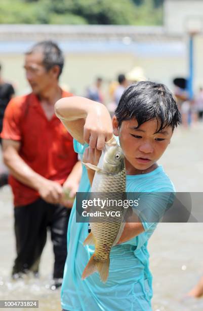 Boy of Miao ethnic group shows caught fish in a river during the Naoyu Festival at Rong'an County on July 20, 2018 in Liuzhou, Guangxi Zhuang...