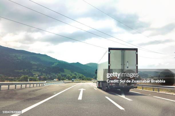 heavy transport. truck traveling on a quiet main road surrounded by nature - meerdere baans snelweg stockfoto's en -beelden