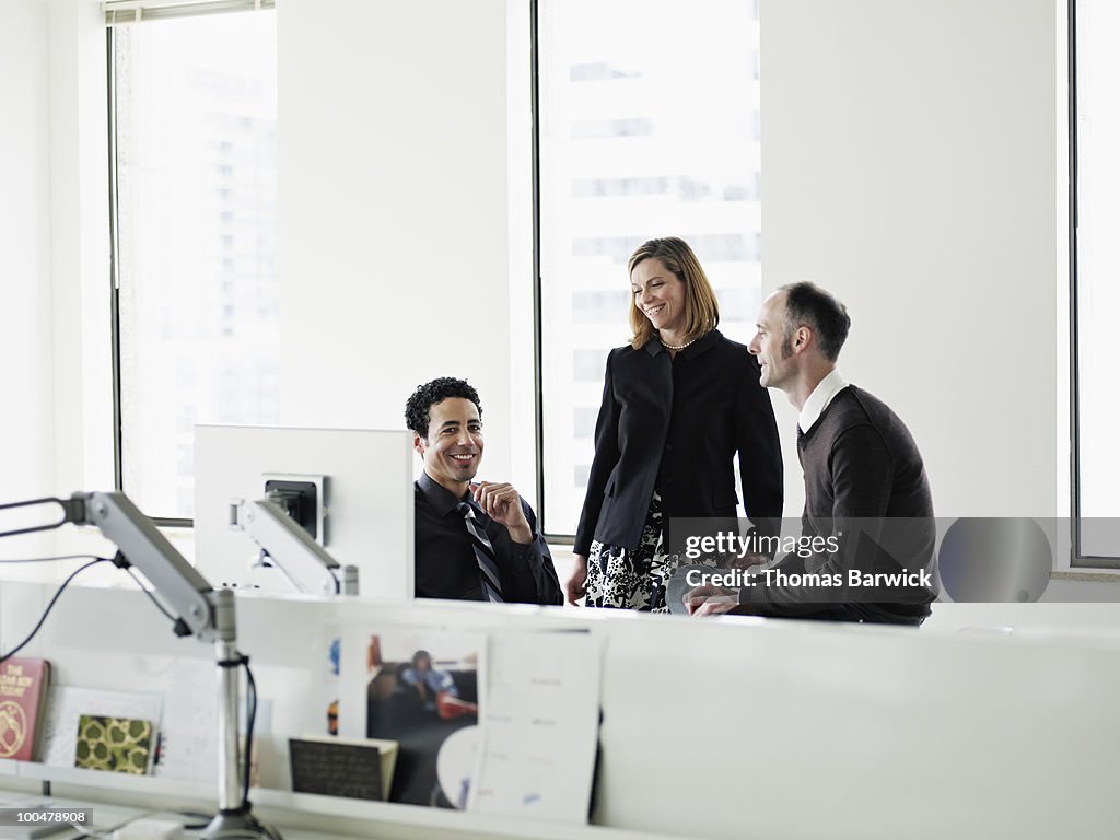 Coworkers in discussion at workstation in office