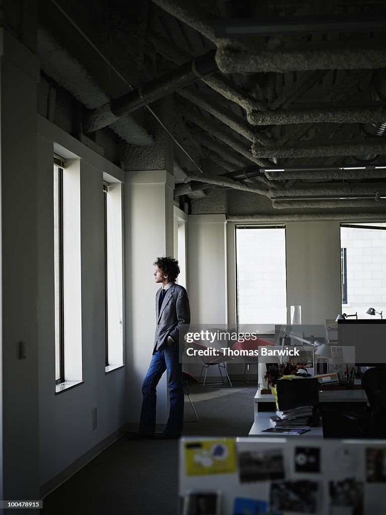 Young businessman standing near window in office