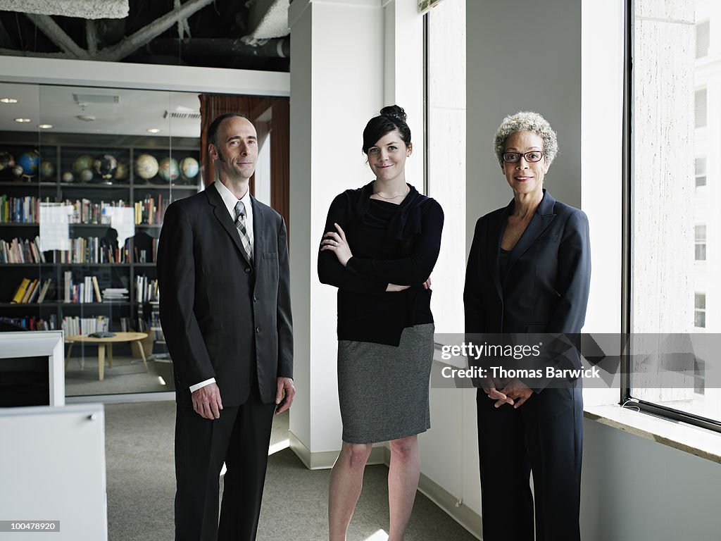 Three coworkers standing in office smiling