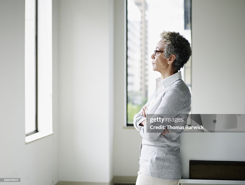 Mature businesswoman in office looking out window