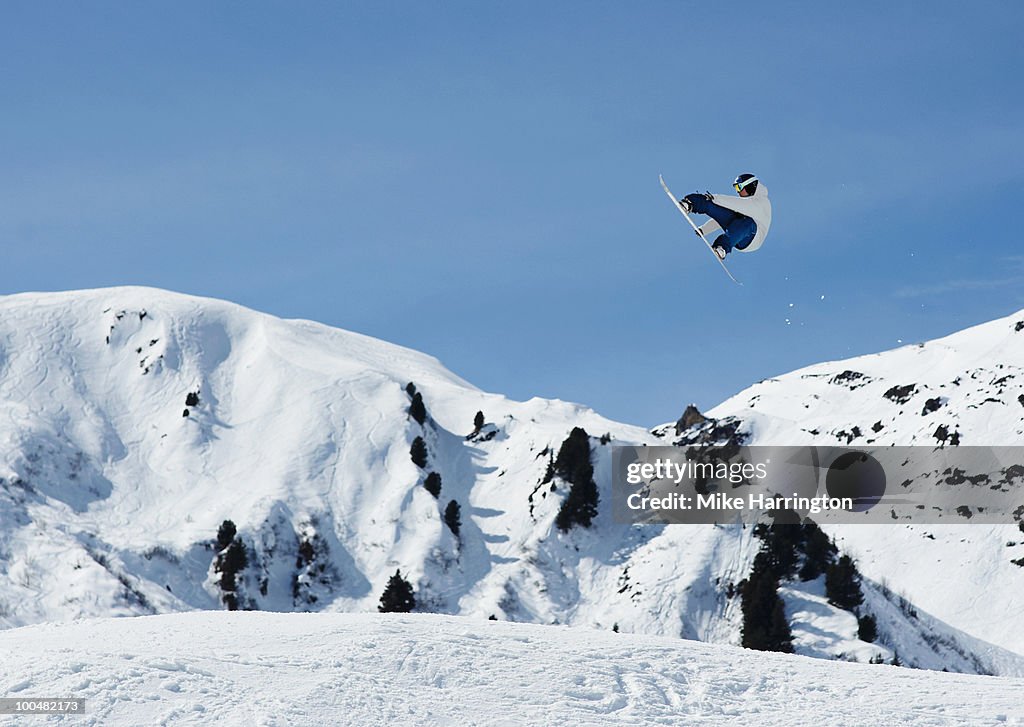 Male snowboarder in the air against blue sky